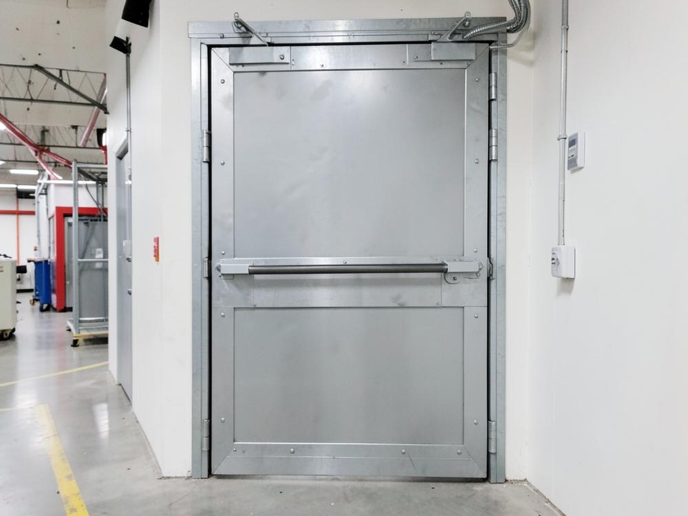 Industrial steel safety door with push bar in a factory corridor